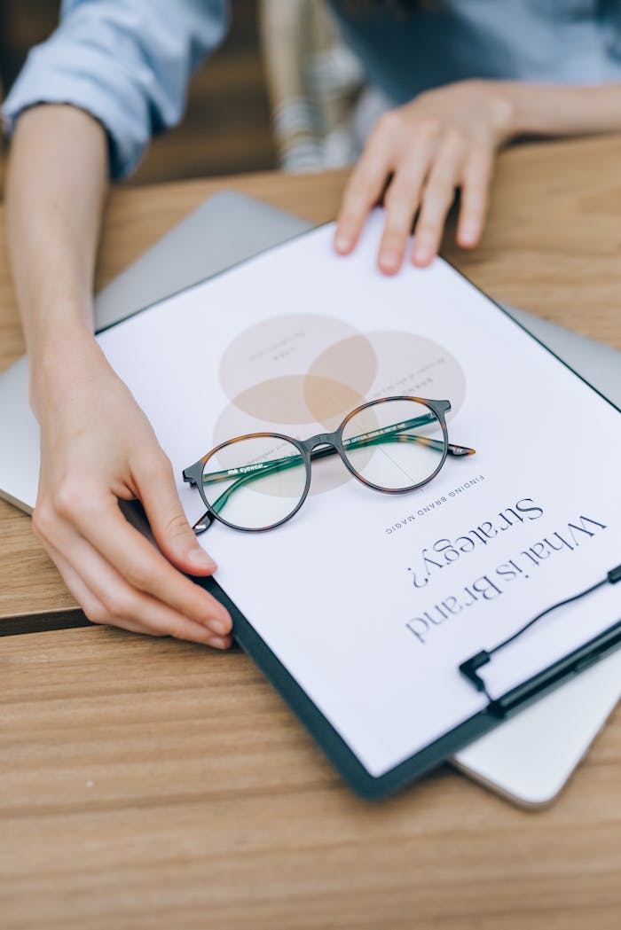 gallery-01 Close-up of eyeglasses on clipboard with brand strategy document, emphasizing business planning and analysis.